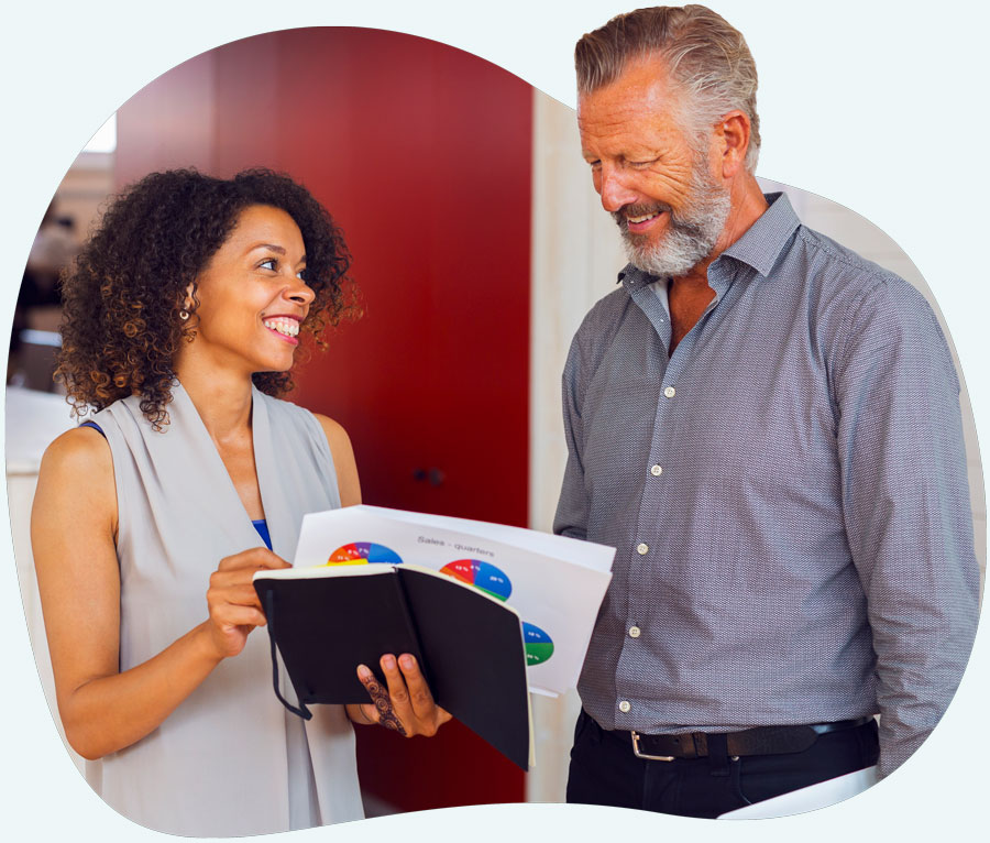 unique-advice-1 Professional mixed-race woman discussing reports with older professional man. Both dressed in smart casual business attire.